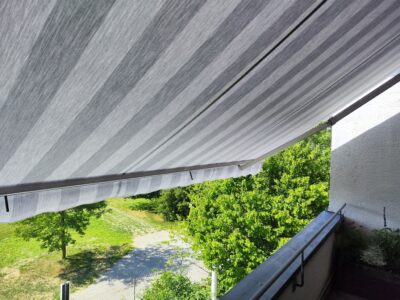 Das neu montierte, graue Markisentuch an einer modern gestalteten Terrasse in Augsburg.