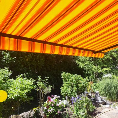 Die erfolgreich erneuerte Markise mit einem strahlenden neuen Stoff an einer Terrasse in Maingründel.