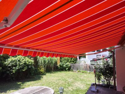 Das neu montierte Markisentuch mit roten Multistreifen wertet die Terrasse in Königsbrunn optisch auf.