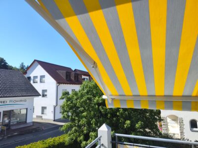 Das neu montierte Markisentuch in Grau-Gelb-Blockstreifen wertet das Haus in Westheim optisch auf.