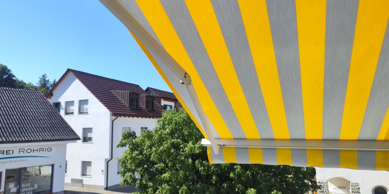 Das neu montierte Markisentuch in Grau-Gelb-Blockstreifen wertet das Haus in Westheim optisch auf.