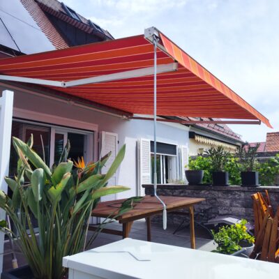 Ein neues Markisentuch mit rotem Multistreifen sorgt auf einer Terrasse in Haunstetten für Schatten.